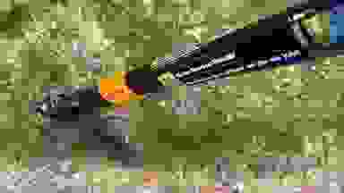 A close-up view of the Fiskars Deluxe Stand-up Weeder in a grassy yard.