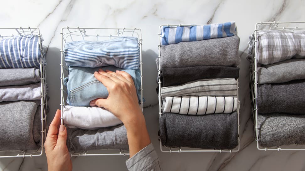 Two hands organizing clothes by using wire baskets.