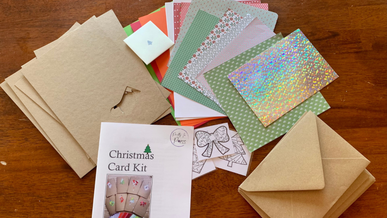 Christmas card kit with instructions, empty cards and envelopes, decorative paper, and templates for the paper cutting.