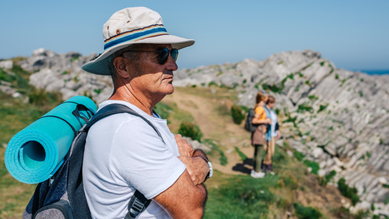 A person wearing a hat looks over a cliff.