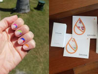 On the left: The author's hand with the Es-cape Verde Mani-Me set applied to the nails. On the right: Two sets of ManiMe nails lay on a wooden table with a hand lotion and sanitizer from the brand on either side of them.