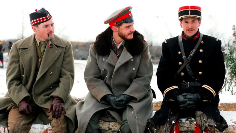 Three solders on the World War I battleflied sit in the snow and discuss life in a scene from Joyeux Noel (2005)