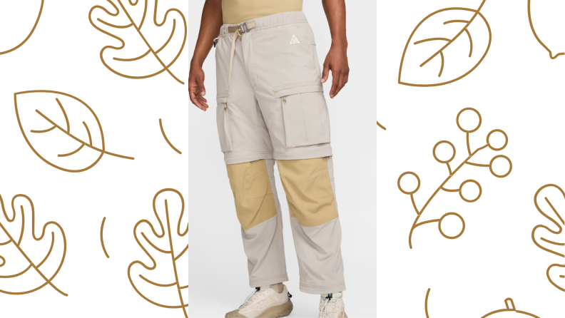 A person stands in a pair of pants from the waist down, over a leaf-printed background