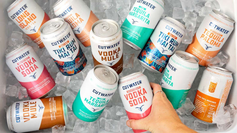 A hand reaches into a cooler filled with hard seltzers.