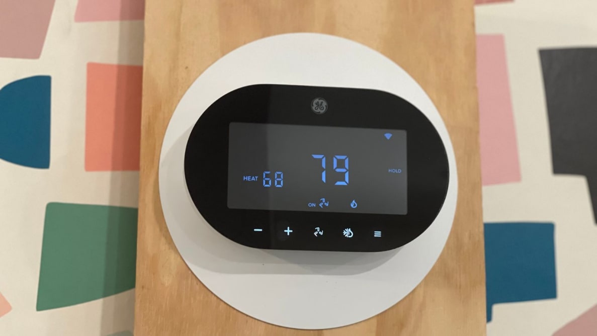 The Cync Smart Thermostat hangs on a piece of wood