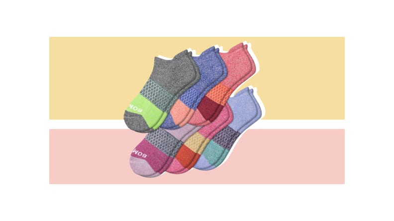 Multiple pairs of socks in various colors against a light gold and pink background.