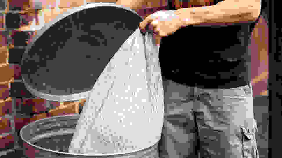 A person putting a trash bag inside of a garbage can.