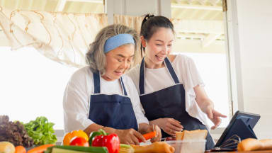 Mother and daughter wearing aprons cooking a meal together