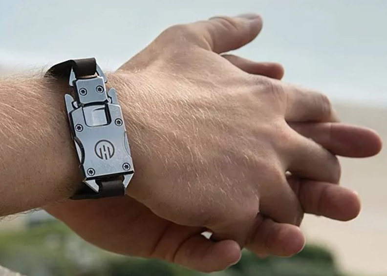 A pair of hands locked around each other, with a utility bracelet around the wrist.
