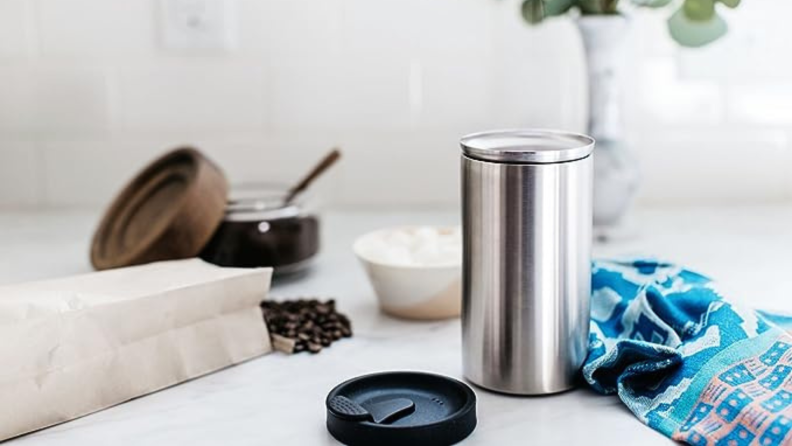 A silver travel mug open on a counter