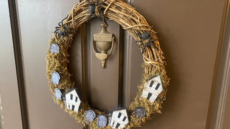A Fraser Hill Farms Halloween wreath, made of vine with haunted houses, tombstones, and black spiders