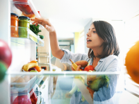 Woman grabbing vegetables from a fridge