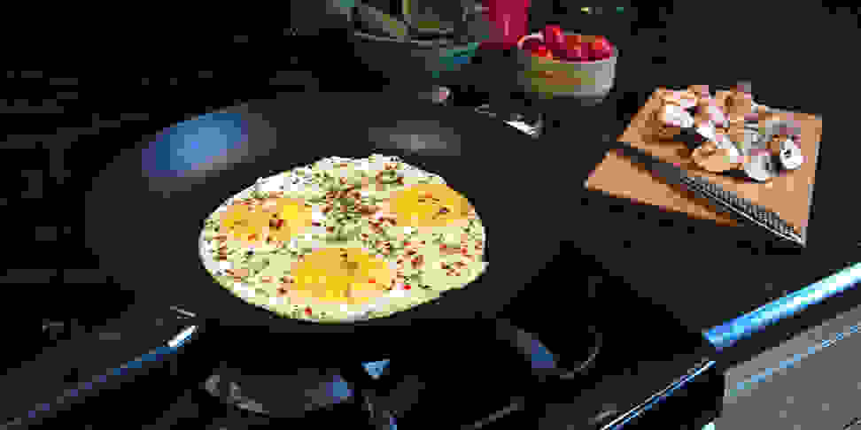 Eggs frying in a nonstick pan on a stovetop.