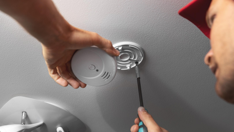 Expert installing a smoke detector on the ceiling
