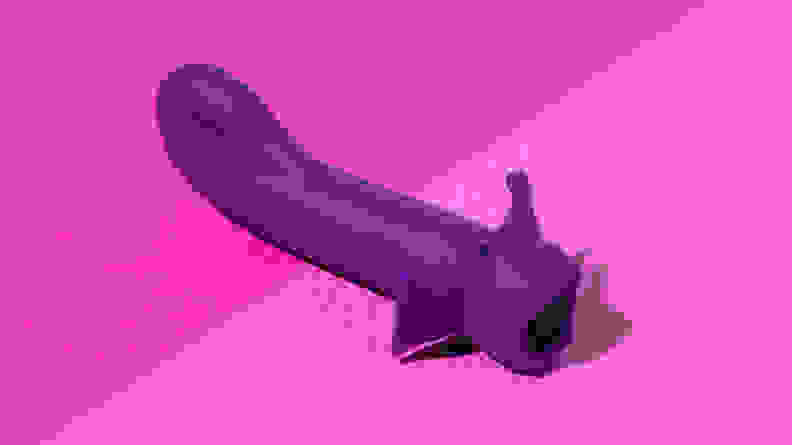 A purple Cute Little Fuckers Shimmer G-spot vibrator on top of a two-tone pink surface.