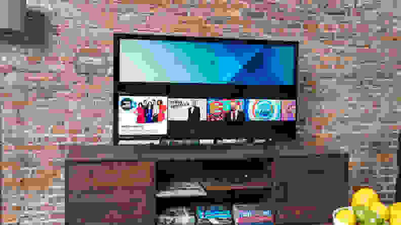 The Samsung Q60A QLED TV displaying its smart platform's home screen in a living room setting