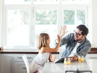 A parent and child high-five in a kitchen.
