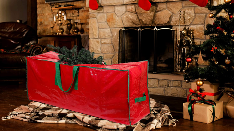 Christmas tree storage bag on living room floor in front of fireplace, next to Christmas tree