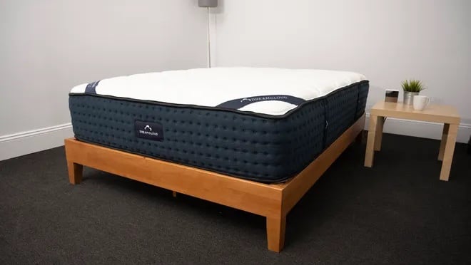 DreamCloud mattress with a woman on top in a bedroom setup.
