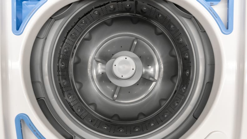 Close-up of the stainless steel drum of the Frigidaire FFTW4120SW washing machine.  In the upper left, top right and lower left corners of the image, you can see the detergent, fabric softener, and bleach trays arranged around the opening of the drum.