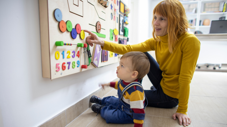 Mother and son play together with a wooden interactive board at psychotherapy office.