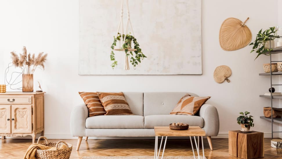 Neutral modern and cozy living room with warm brown accents and a hanging plant over the a gray couch