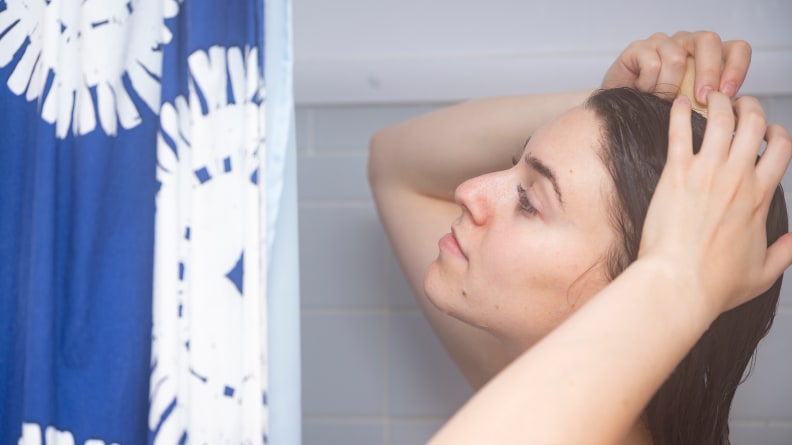 A closeup of a person holding the HiBar Volumize Shampoo Bar up to their wet hair in the shower.