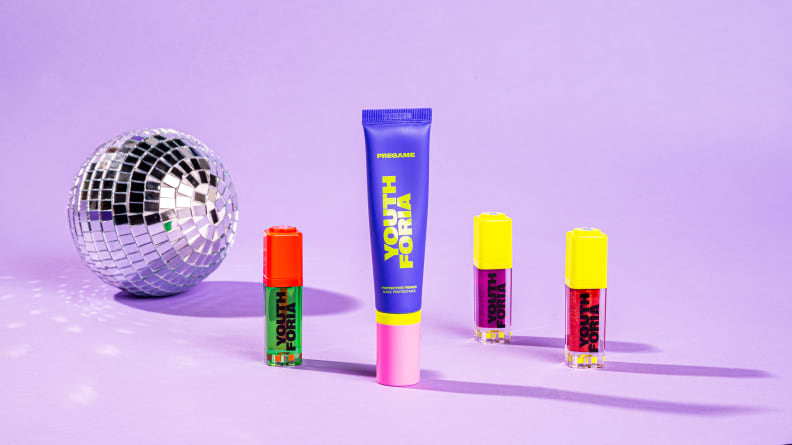 A disco ball sits next to an array of four Youthforia products against a lavender background.