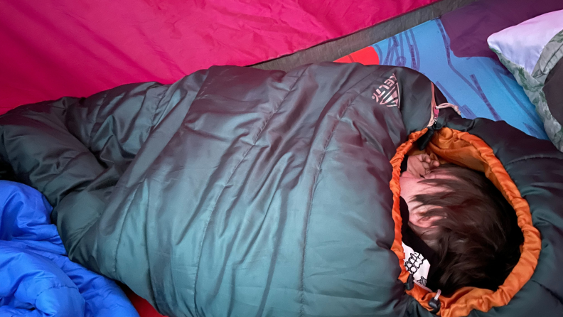 A child sleeps in a Kelty Mistral bag