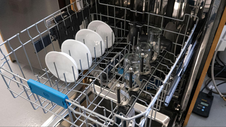 The upper rack of a dishwasher with dishes and glassware.