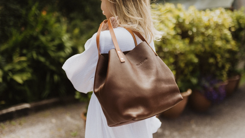 A woman carrying a leather tote bag