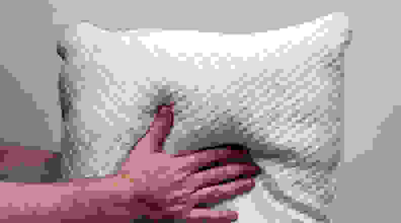 Two hands fluffing the Xtreme Comforts pillow