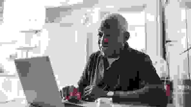 An older man smiles at a laptop screen