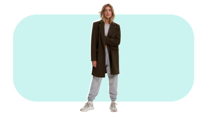 A model wearing an olive green wool coat with a gray sweatsuit.