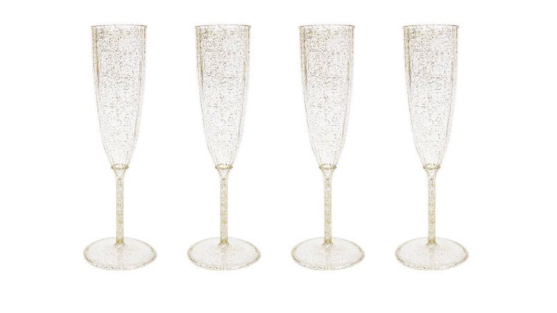 Four plastic champagne flutes with gold glitter.