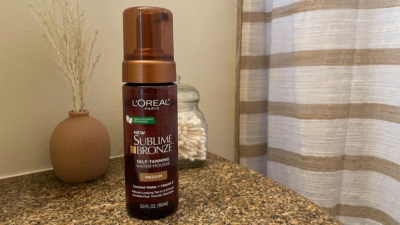 The L'Oréal Paris Sublime Bronze Self Tanning Water Mousse self-tanner sitting on a bathroom sink.