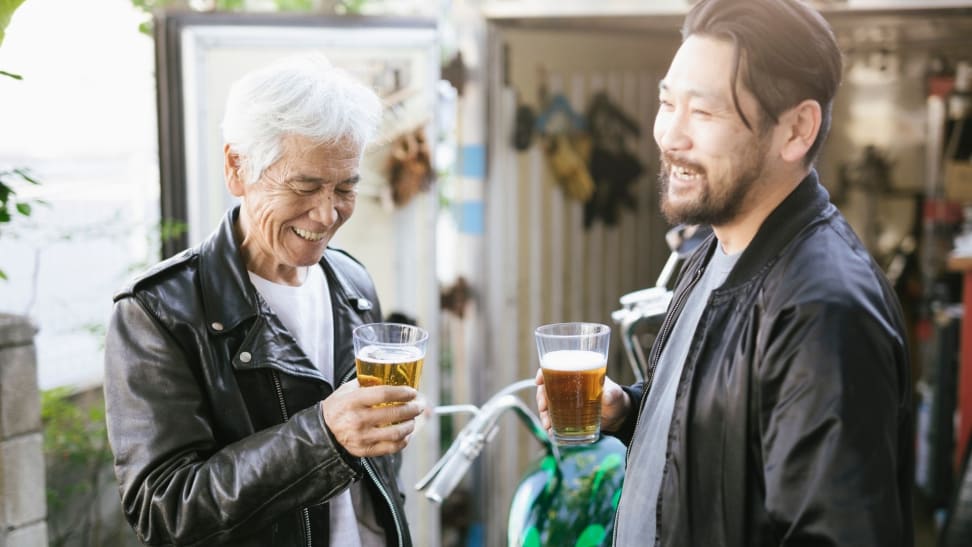 Father and son enjoy a beer outdoors.