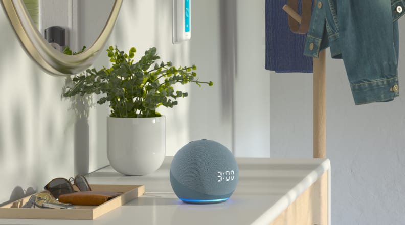 Twilight blue Echo Dot with Clock on table next to potted plant