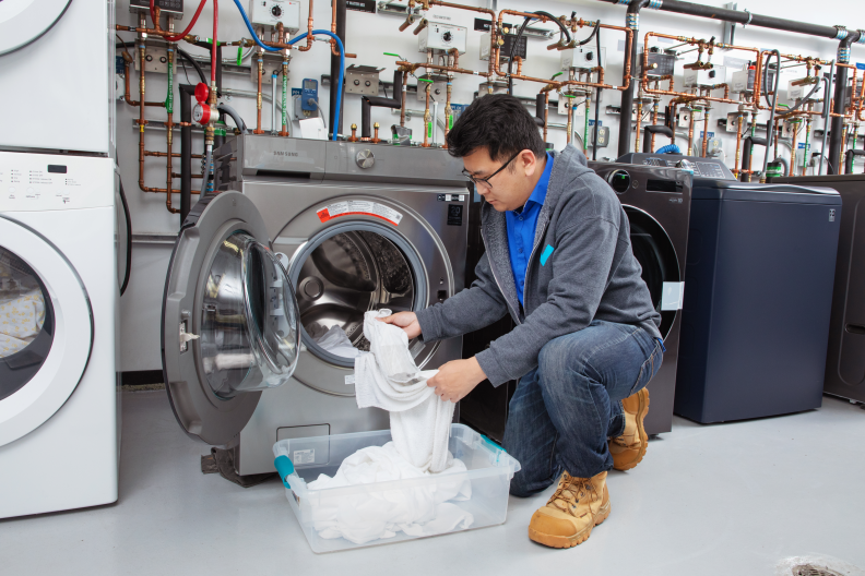 A person loading the front washer with laundry.