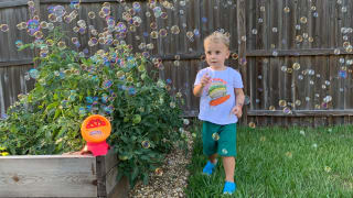 A toddler runs through bubbles outside