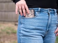 Girl wearing American Eagle jeans slides her cell phone into her pocket.