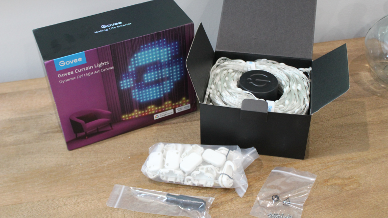 The packaging of the Govee Curtain Lights sits open on a table showing all of the items that come with the lights.