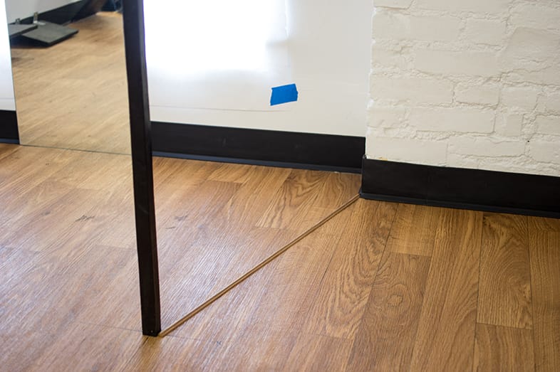 A wooden room threshold and stand up mirror in the robot vacuum testing arena.