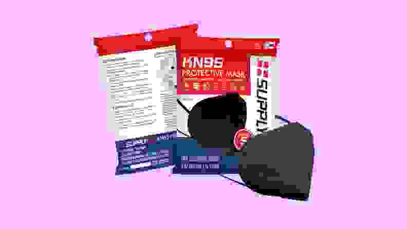 A black SupplyAID KN95 face mask next to its packaging on a purple background.