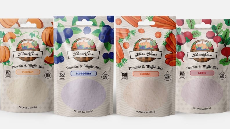 Four packages of pancake mix are arranged across a white background in the following flavor order from left to right: pumpkin, blueberry, carrot, and beet.
