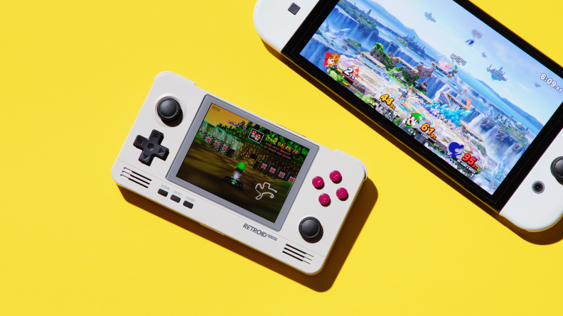A small handheld gaming console on a yellow background next to the nintendo switch
