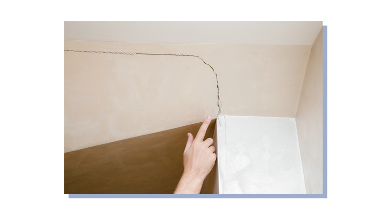 Person using finger to point out long crack in ceiling foundation.