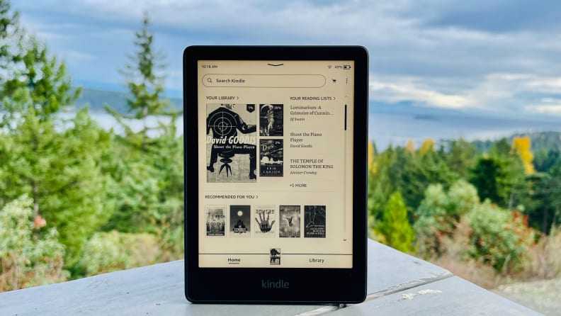 A Kindle Paperwhite sits on an outdoor table against an overcast sky.
