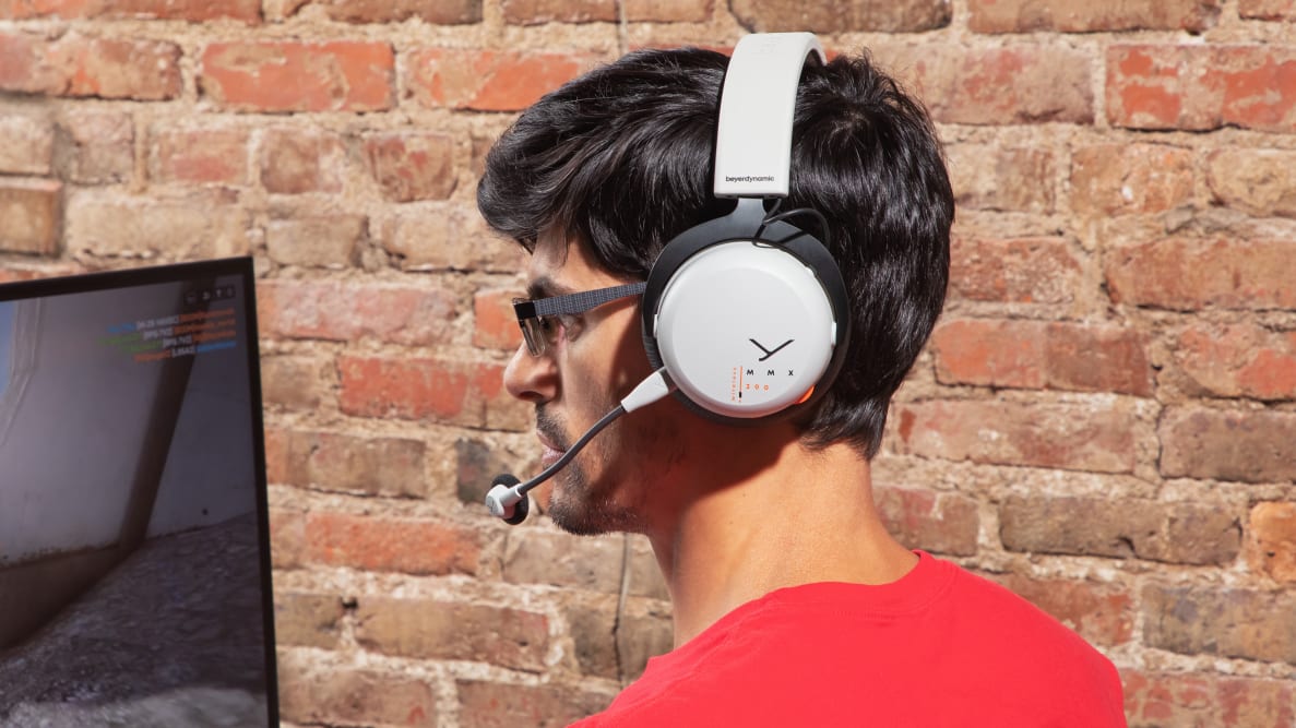 The Beyerdynamic MMX 200 headphones being worn on a head against a brick backdrop