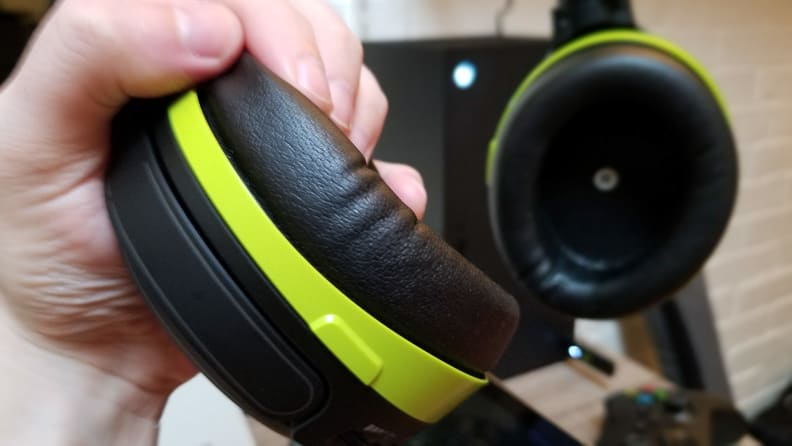 Close-up: A hand grips one of the earphones of a gaming headset.